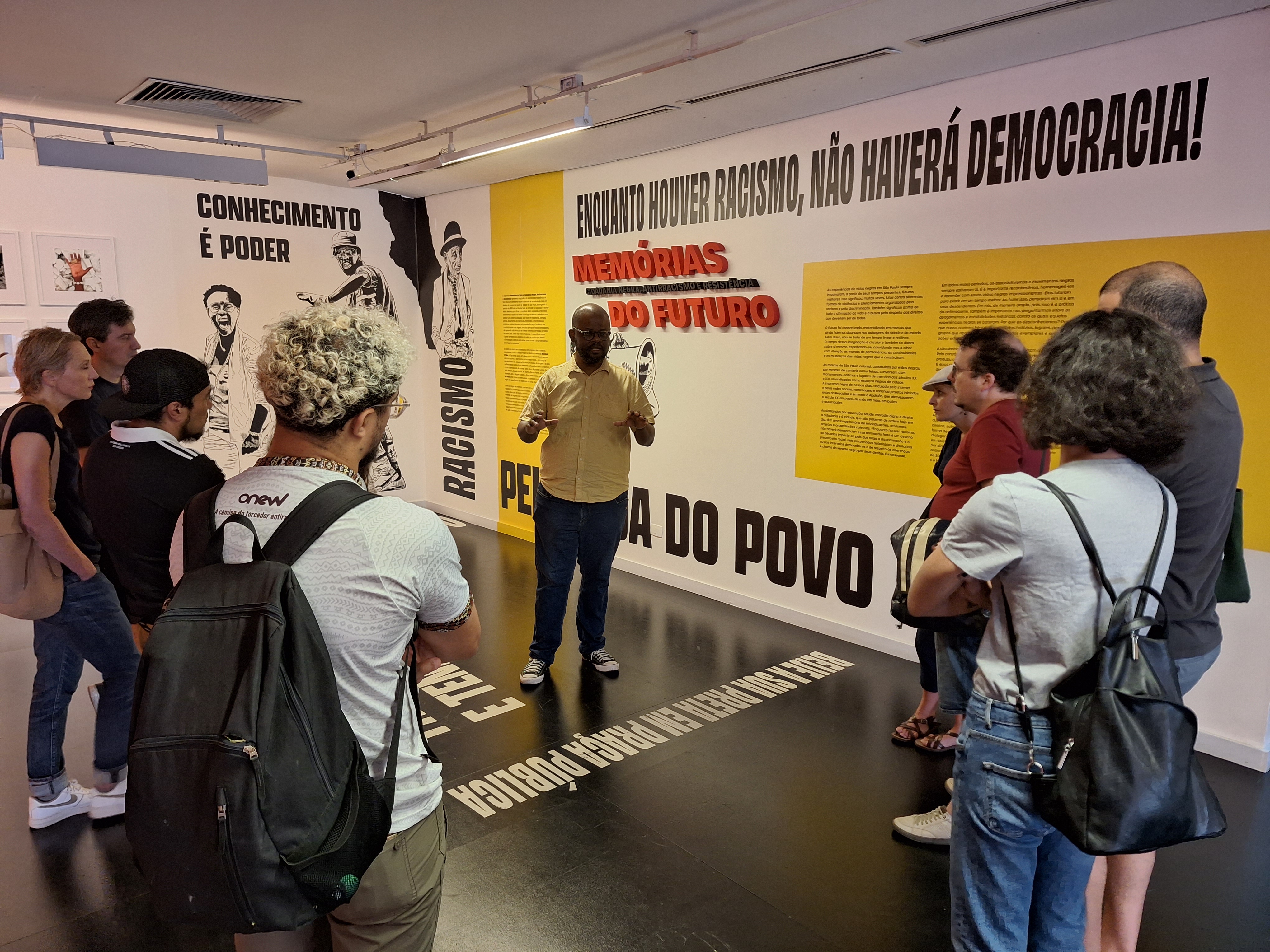 Ein Mann führt eine Gruppe durch eine Ausstellung (öffnet Vergrößerung des Bildes)