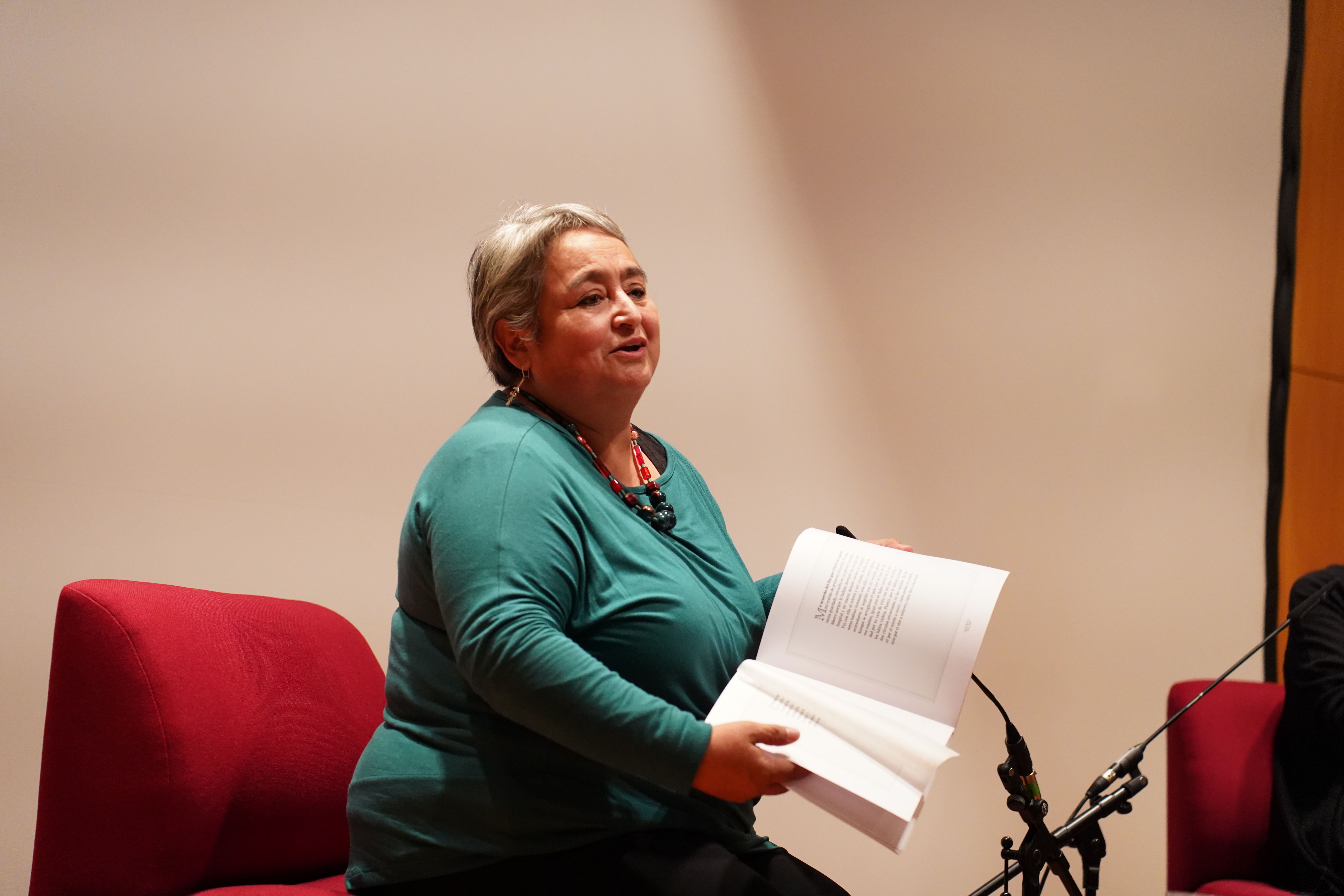 Rosabetty Muñoz hojea su libro de poemas en el escenario (abre una ampliación de la imagen)