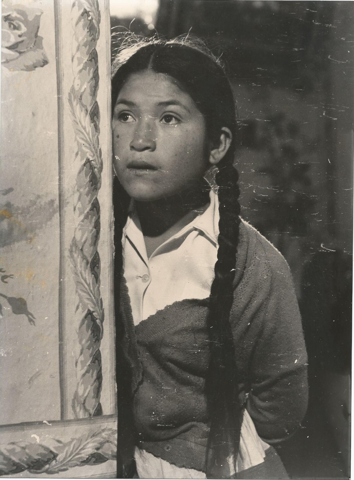 En Mädchen mit langen Zöpfen steht in einem Türrahmen