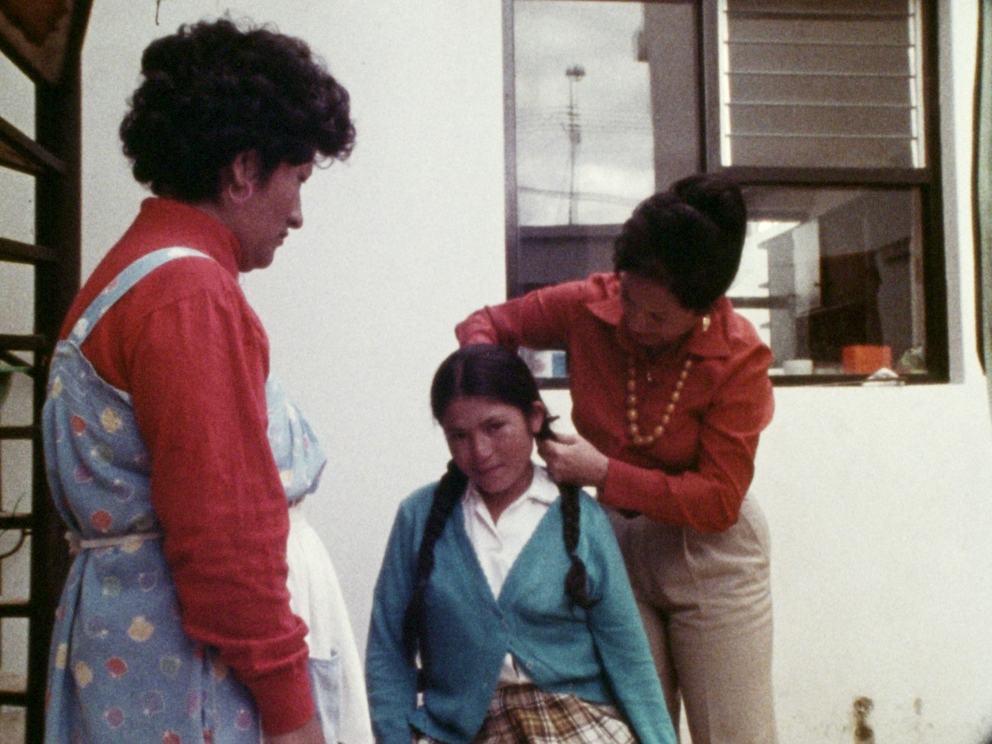 Ein Mädchen bekommt von einer Frau seine Zöpfe abgeschnitten