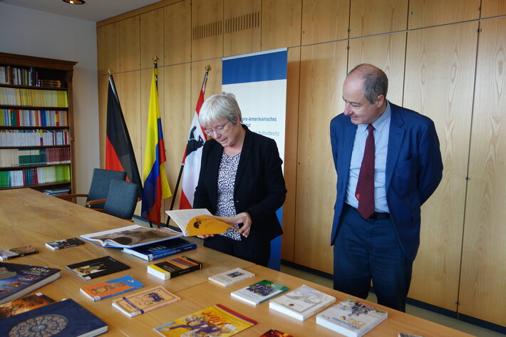 Zwei Personen betrachten auf einem Tisch liegende Bücher