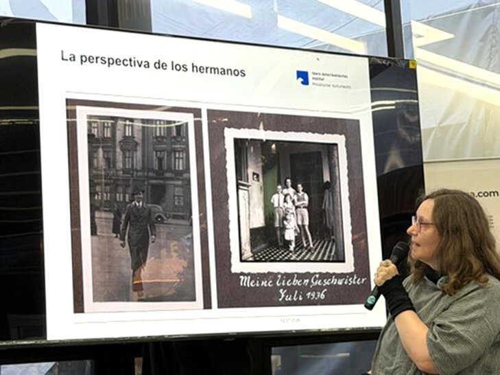 Eine Frau präsentiert auf einer Leinwand historische Familienfotos (öffnet Vergrößerung des Bildes)