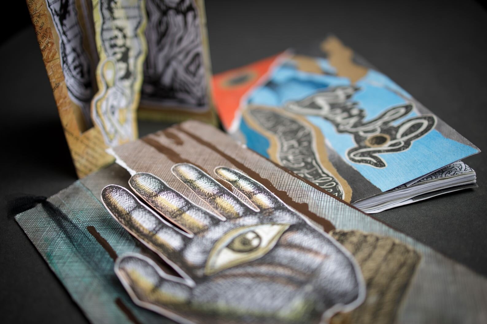 Detail of a book with a cut-out collage showing a hand with an eye