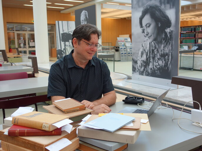 El investigador invitado Alexandre Fortes con libros y un portátil en su puesto de trabajo en la sala de lectura