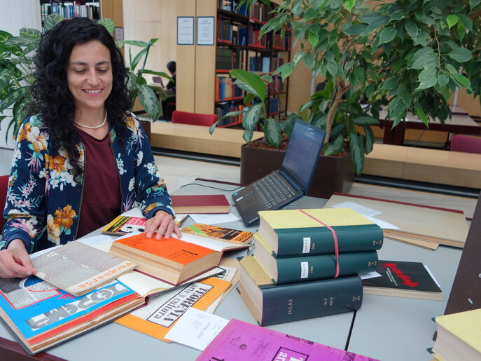 La investigadora visitante Sandra Restrepo se sienta en la biblioteca del IAI, rodeada de libros y un ordenador portátil.