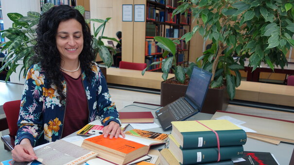 Gastwissenschaftlerin Sandra Restrepo mit Büchern an ihrem Arbeitsplatz im Lesesaal