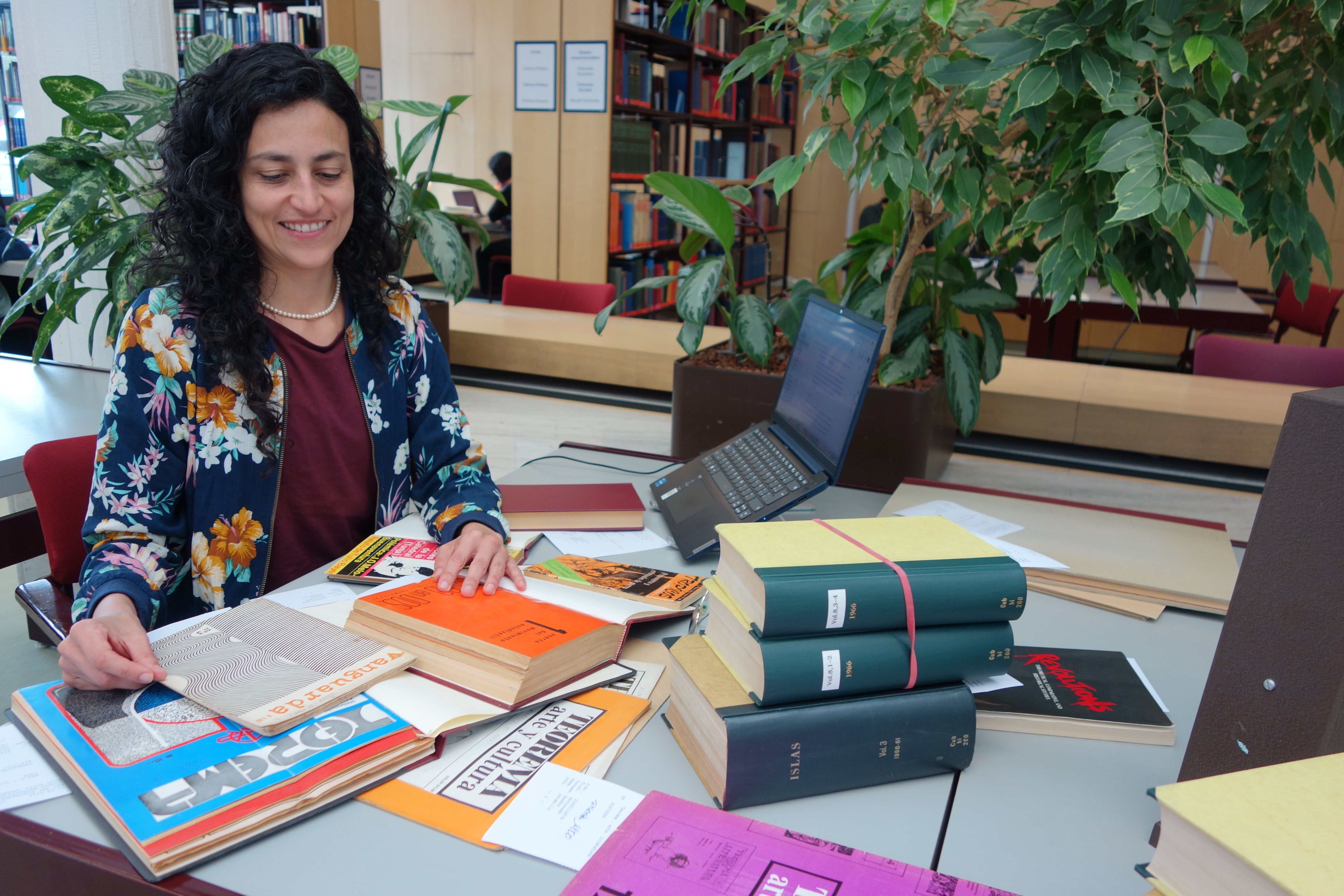 A pesquisadora convidada Sandra Restrepo com livros em sua estação de trabalho na sala de leitura