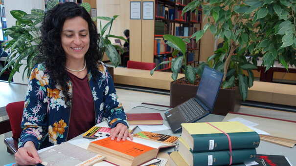 La investigadora invitada Sandra Restrepo con libros en su puesto de trabajo en la sala de lectura