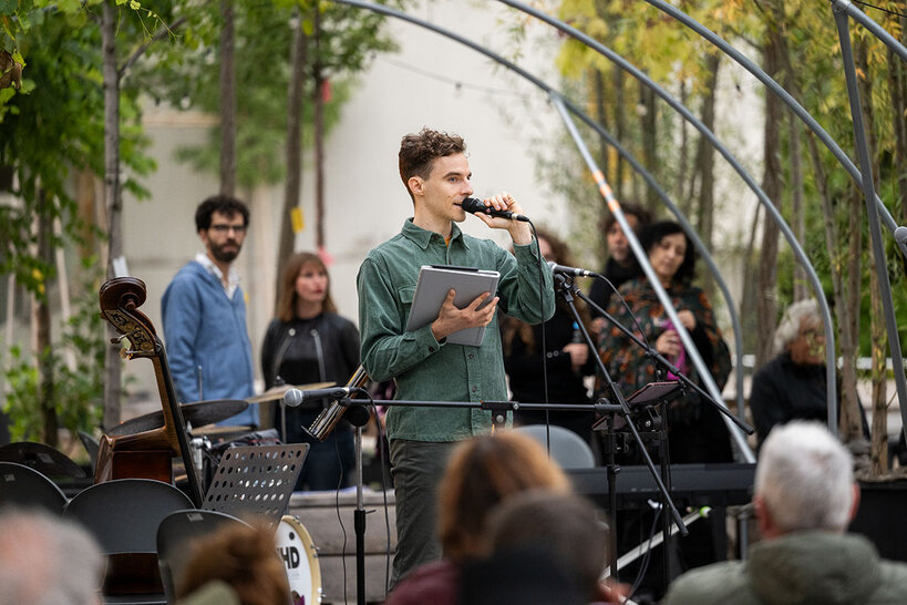 Sänger mit weiteren Musiker*innen auf einer Bühne unter freiem Himmel