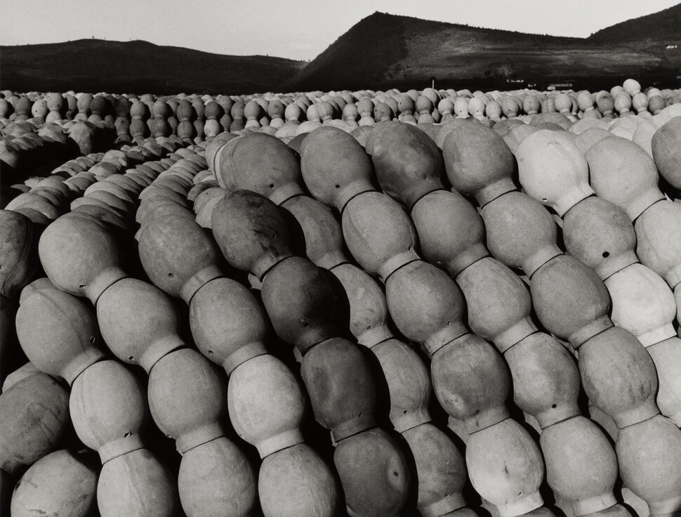 Black-and-white photograph of stacked small clay vessels