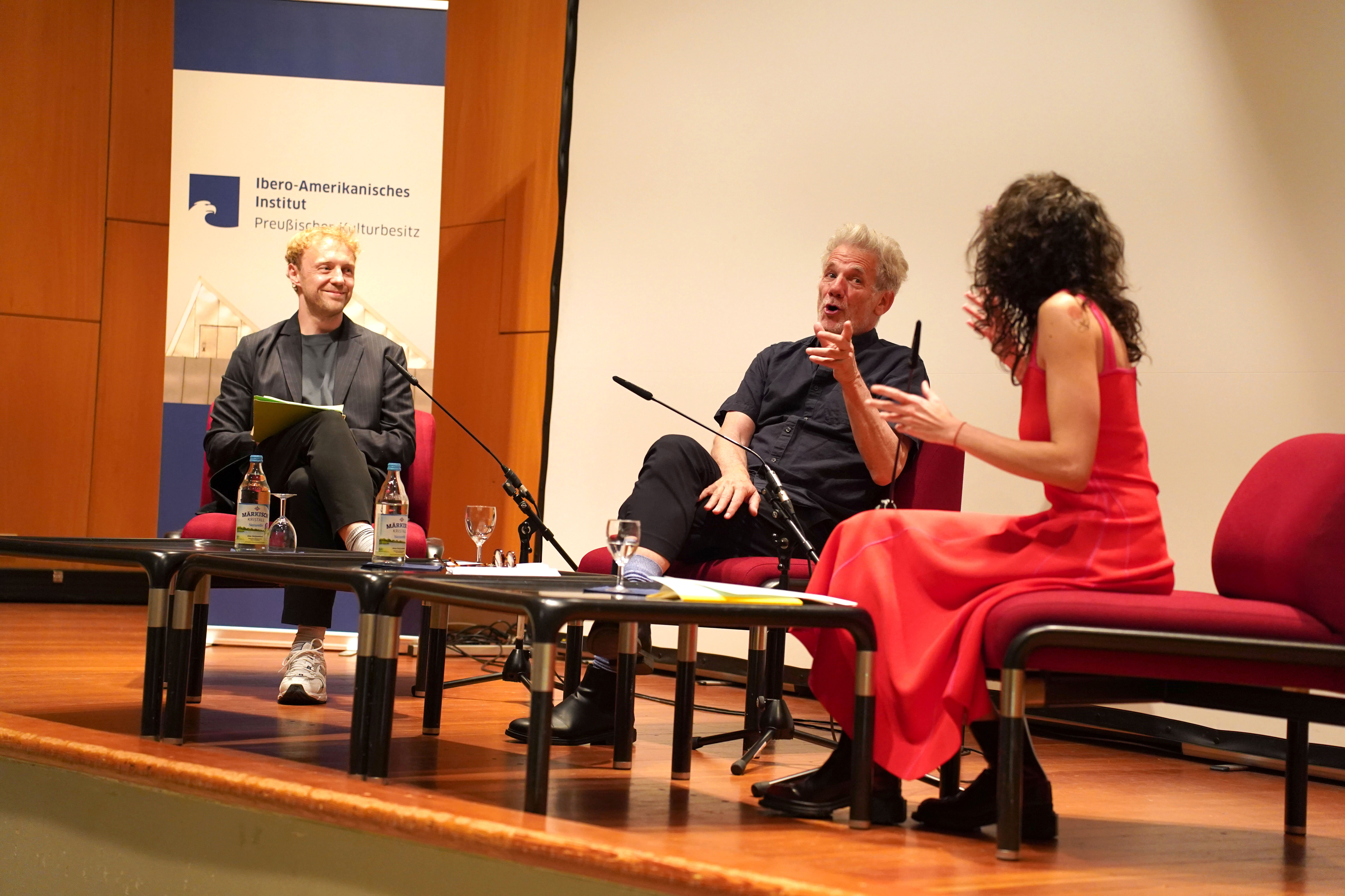 Tres personas conversando en un escenario