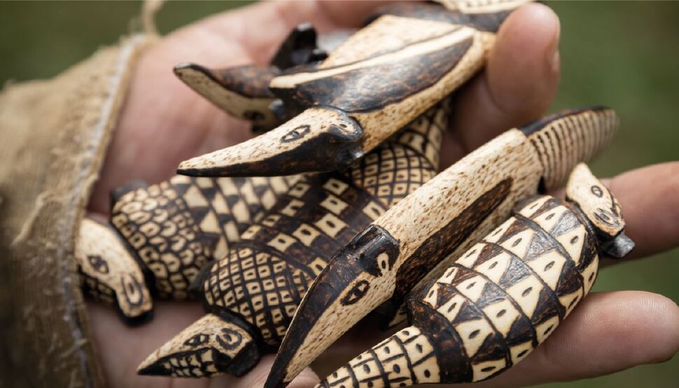 Uma mão segura vários pequenos animais esculpidos com pintura a pirógrafo (abre uma ampliação da imagem)