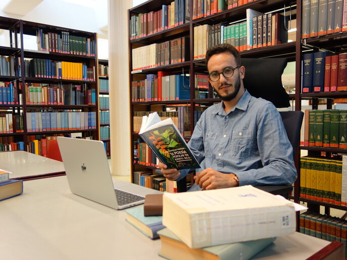El investigador invitado Ewerton Barros con libros en su puesto de trabajo en la sala de lectura