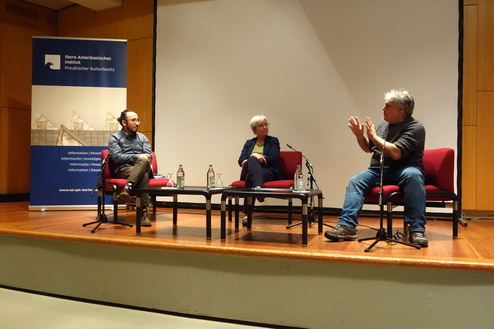 Tres personas sentadas en un escenario