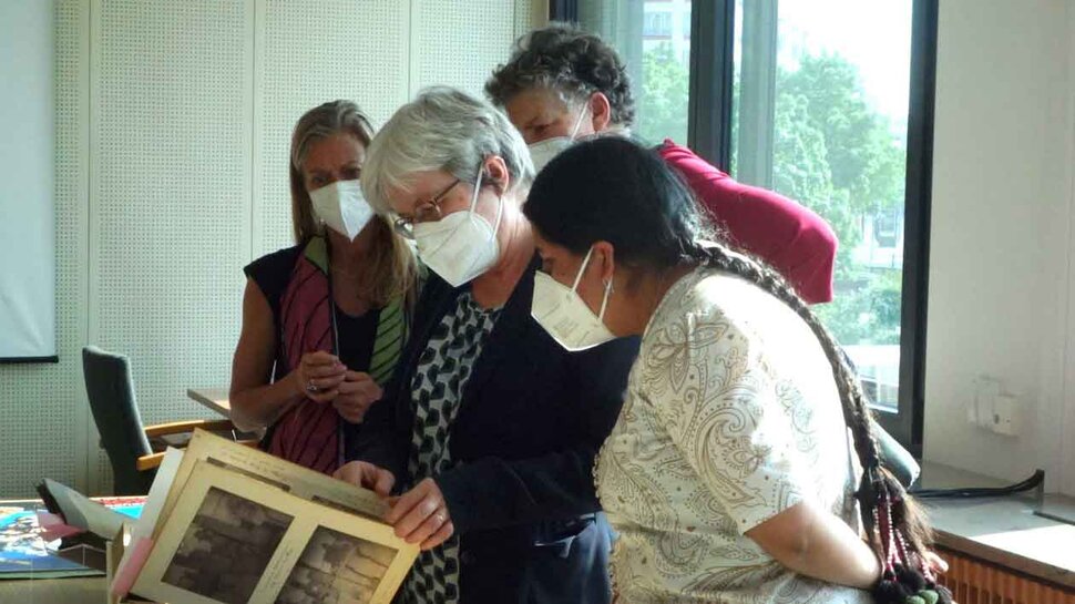 Elvira Espejo Ayca and Barbara Göbel look at a historical photo album