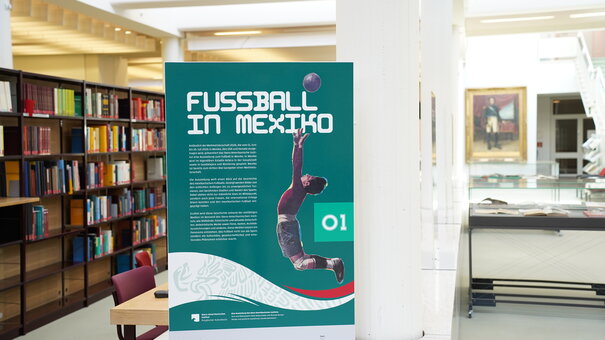 Eine Ausstellungstafel vor einem Bücherregal