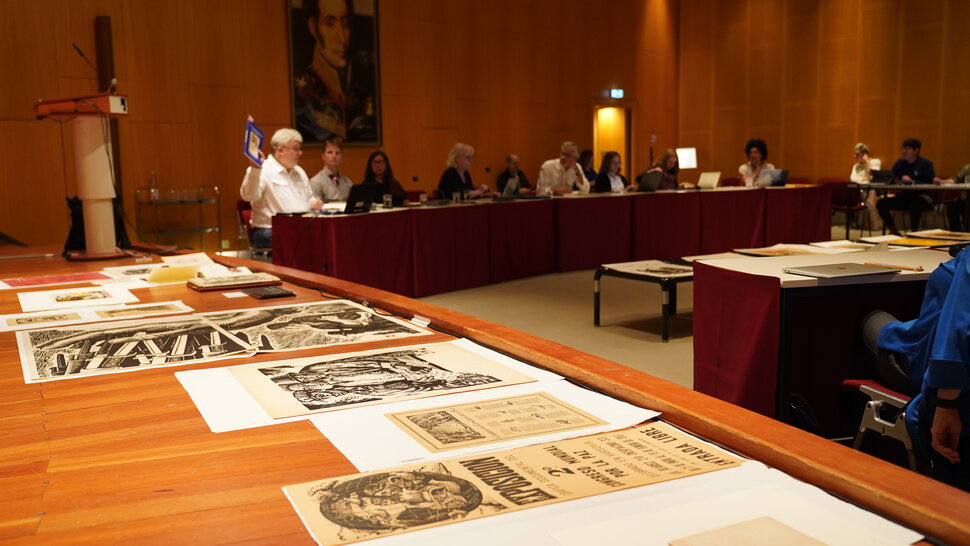 Menschen bei einer Konferenz und historische Drucke (öffnet Vergrößerung des Bildes)